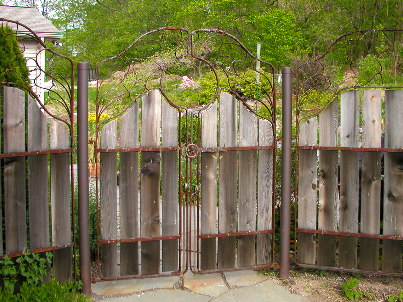 A rustic custom gate and fence panels made from wrought iron cedar and copper