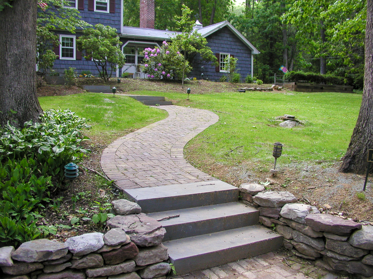 Winding path through front yard with mixed materials and low stone walls