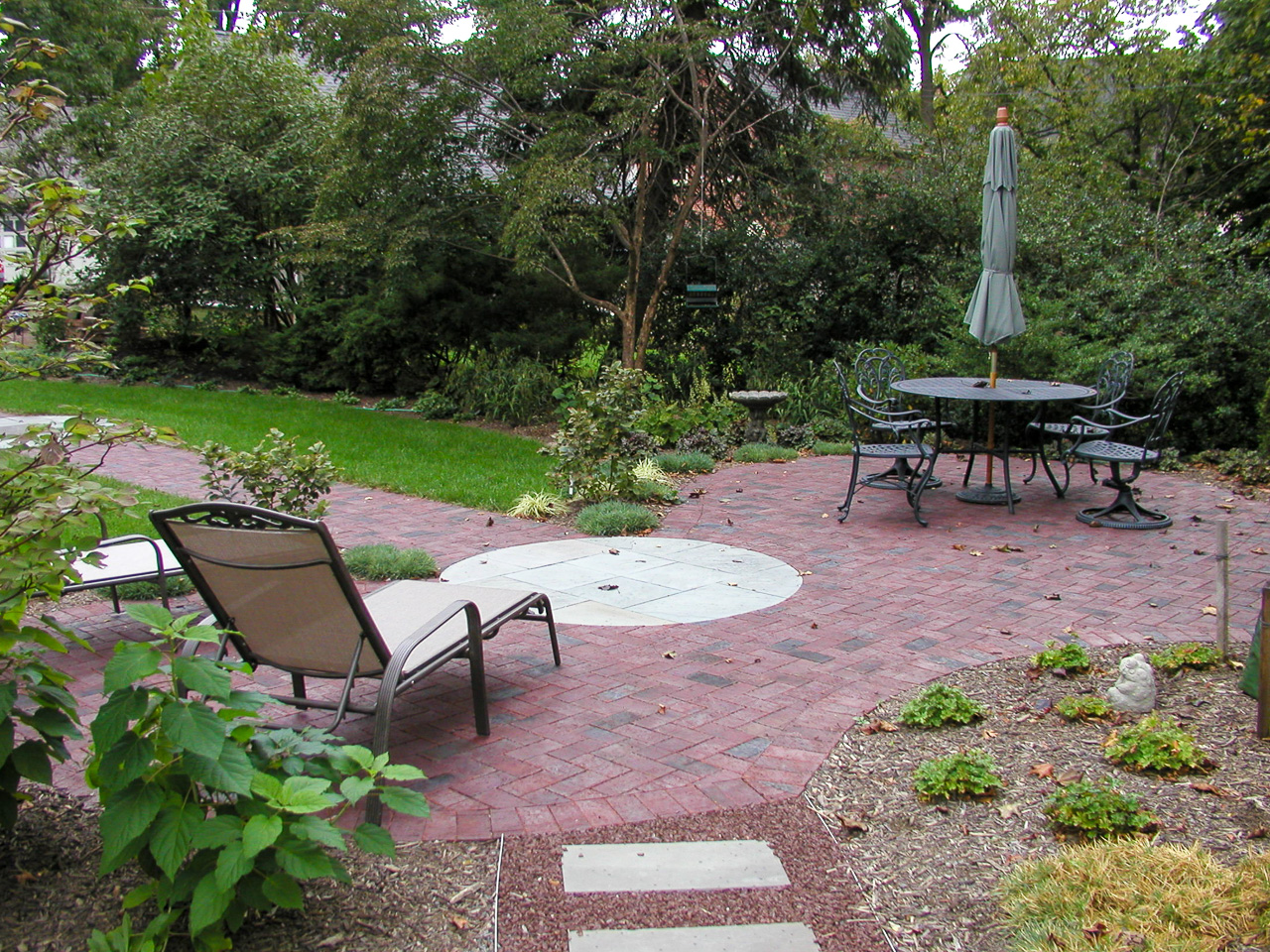 Backyard patio and path confluence with multiple materials and a circular feature flagstone element as a hub